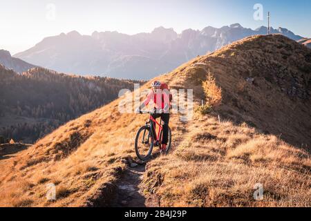 Ein Mann fährt auf den Gleisen im Tal von San Nicolò, Fassa, Trentino, in den Bergen, in Italien mit einem Fahrrad MTB Stockfoto