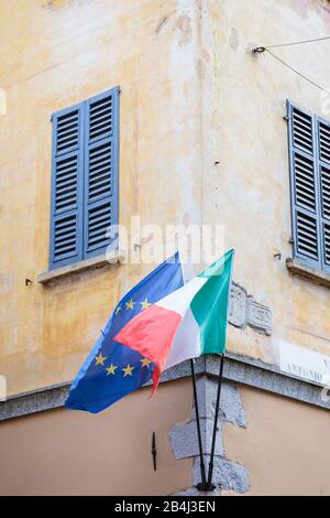 Europa, Italien, Piemont, Cannobio. Eine Hausecke hat die italianischen und die europäischen Flaggen. Stockfoto