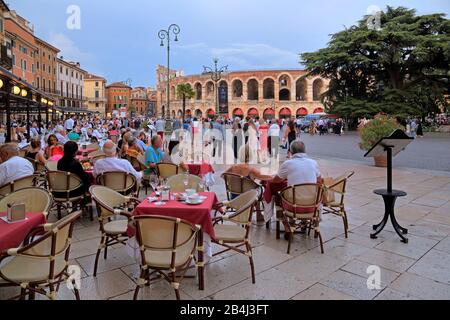 Piazza Bra mit Restaurantterrasse und Amphitheater Arena di Verona in der Dämmerung, historisches Zentrum, Verona, Venetien, Italien Stockfoto