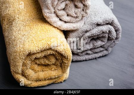 Drei gerollte, gefaltete Handtücher in Pastellfarben auf grauem Hintergrund. Stockfoto