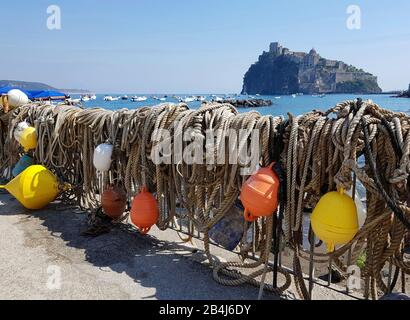 Ischia Ponte, Fischernetze hingen trocken, im Hintergrund das Castello Aragonese, die Burg Aragon, das Meer und Boote. Stockfoto