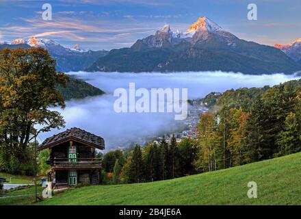 Landschaft mit Morgennebel über Ort und Tal gegen Funtenseetauern (2579m), Schönfeldspitze (2653m) und Watzmann (2713m) bei Sonnenaufgang, Berchtesgaden, Berchtesgadener Land, Oberbayern, Bayern, Deutschland Stockfoto