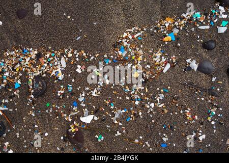 Mikroplastik auf dunklem Lavasand, Sandstrand, Playa Famara, Lanzarote, Kanarische Inseln, Spanien Stockfoto