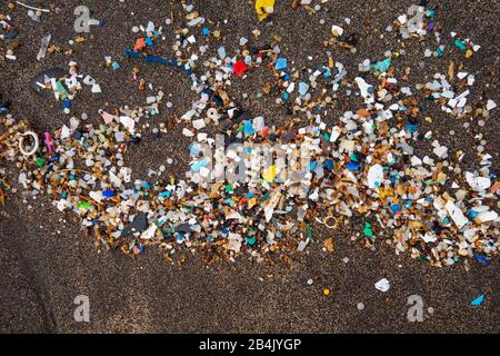 Mikroplastik auf dunklem Lavasand, Sandstrand, Playa Famara, Lanzarote, Kanarische Inseln, Spanien Stockfoto