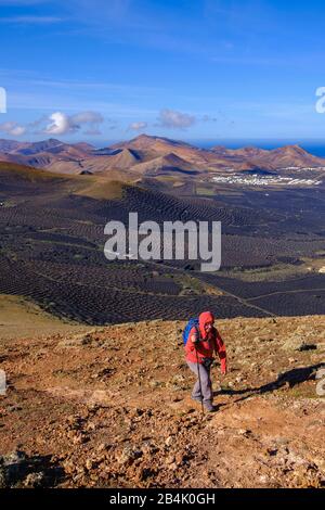 Frau wandert auf dem Bergweg nach Montana de Guardilama, in Yaiza, Weinanbaugebiet La Geria, Lanzarote, Kanarische Inseln, Spanien Stockfoto