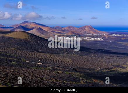 Weinberge am Berghang, Dörfer Uga und Yaiza, Berge Atalaya de Femes und Montana del Medio, Weinregion La Geria, Lanzarote, Kanarische Inseln, Spanien Stockfoto