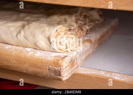 Teigrollen mit Apfelfüllung liegen auf einem Holzbrett, apfelstrudel, Backwaren. Stockfoto