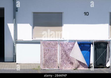 Abfallbehälter aus Kunststoff stehen unter einer metallischen Struktur mit Vorhängen. Stockfoto