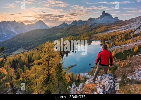 Ein Mann, der an einem Herbstmorgen auf den See Federa blickt, die berge, cortina d'ampezzo, belluno, venetien, italien Stockfoto