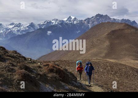 Wandern mit Rucksacktouristen Lupra Pass auf dem Annapurna Circuit Wanderung in der Alpenlandschaft mit entferntem schneebedecktem Himalaya Mountain Peak auf Horizon Stockfoto