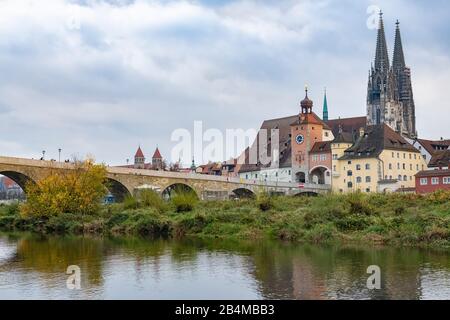 Deutschland, Bayern, Regensburg, Blick von der Jahninsel auf die Donau, Steinerne Brücke und Altstadt mit Welterbe-Besucherzentrum und Dom im Herbst Stockfoto