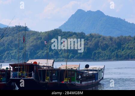 Luang Prabang, Laos - 2019-11-18: Lange Boote und Lastkähne ankerten am Ufer des Mekong River. Stockfoto