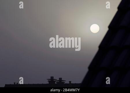 Die Sonne hinter dicken Wolken im dunkelgrauen Himmel Stockfoto