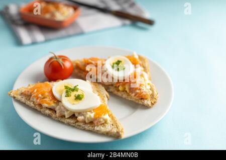 Ein köstlicher Räucherlachs, der aus Joghurt und Gewürzen auf einem ganzen Korn Brot Toast mit einer Tasse Kaffee auf der Seite zubereitet wird. Stockfoto