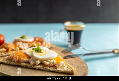 Ein köstlicher Räucherlachs, der aus Joghurt und Gewürzen auf einem ganzen Korn Brot Toast mit einer Tasse Kaffee auf der Seite zubereitet wird. Stockfoto