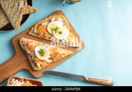 Ein köstlicher Räucherlachs, der aus Joghurt und Gewürzen auf einem ganzen Korn Brot Toast mit einer Tasse Kaffee auf der Seite zubereitet wird. Stockfoto