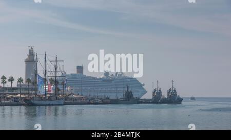 Das historische Segelschiff - Oele Marite - vor Anker in Málaga. Im Hintergrund der Leuchtturm und ein Kreuzfahrtschiff Stockfoto