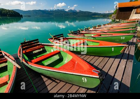 Ruderboote am Walchensee, türkisfarbenes Wasser im Hintergrund und die Berge der deutschen Alpen. Stockfoto