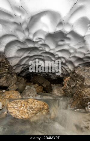 Schneeschmelze und eine Höhle an einem kleinen Bach im Karwendel im Frühsommer Stockfoto