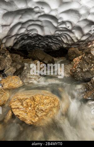 Schneeschmelze und eine Höhle an einem kleinen Bach im Karwendel im Frühsommer Stockfoto