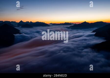 Die Lichter von Maurach und Pertisau am Achensee leuchten während einer Langzeit-Nacht unter dem Meer von Wolken des aufsteigenden Hochnebels durch. Im Hintergrund das Karwendelgebirge, das vom Ebener Joch im Rofan eingenommen wurde. Stockfoto