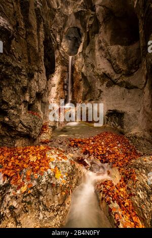 Ein kleiner Bach auf dem Kesselberg bei Kochel am See mit einem Durchbruch im Felsen und Wasserfall im Herbst. Stockfoto