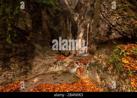 Ein kleiner Bach auf dem Kesselberg bei Kochel am See mit einem Durchbruch im Felsen und Wasserfall im Herbst. Stockfoto