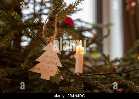 Fröhliche Weihnachten steht auf einem Holzweihnachtsbaum, dekorierter Weihnachtsbaum Stockfoto