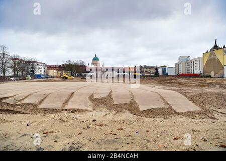 03. März 2020, Brandenburg, Potsdam: Hinter dem Portal der Garnisonkirche (r) erstreckt sich ein abgeflachter sandiger Bereich. Im Hintergrund ist die Kirche St. Nikolai (M) am Alten Marktplatz zu sehen. Die Kirche wurde in den Jahren von 1730 bis 1735 nach den Plänen des Architekten Philipp Gerlach erbaut und galt als ein Hauptwerk des preussischen Barock. Nach der Bombardierung durch die Alliierten am 14. April 1945 blieben nur noch Ruinen übrig, die erst 1968 gesprengt und abgetragen wurden. Der Umbau der Garnisonkirche beschränkt sich auf den Kirchturm, der bis Sommer 2022 fertiggestellt werden soll. Foto: Stockfoto