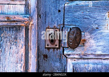 Detail der alten blauen Holztür mit Schlüsselloch und Türknopf. Beaumont-en-Auge im Département Calvados in der Region Normandie Stockfoto