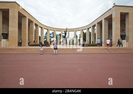 Der amerikanische Militärfriedhof Saint-Laurent am Omaha Beach in der Normandie bei Colleville-sur-Mer. Halbrunde Säulenreihe mit einer sieben Meter hohen Bronzestatue "Der Geist der amerikanischen Jugend Steigt aus den Wellen". Stockfoto