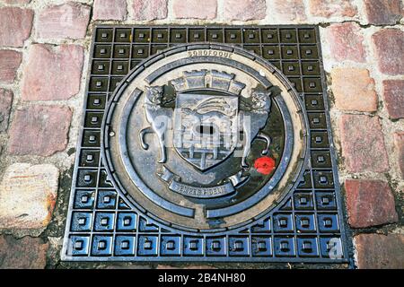 Saint-Malo ist eine Hafenstadt an der Cote d-'Emeraude in der Bretagne im Nordwesten Frankreichs. Rustikale Mannhole-Abdeckung mit dem Stadtwappenbild. In den Kopfsteinpflaster der Altstadt. Stockfoto