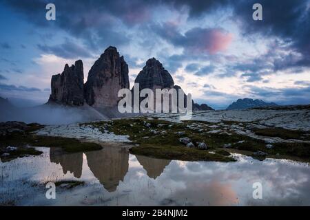 Drei Zinnen, Sextner Dolmen, Südtirol, Italien, die Bergkette der drei Gipfel spiegelt sich nach Regenschauer in Pfütze wider Stockfoto