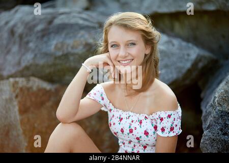 Junges Mädchen sitzt auf Steinen Stockfoto