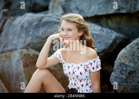 Junges Mädchen sitzt auf Steinen Stockfoto