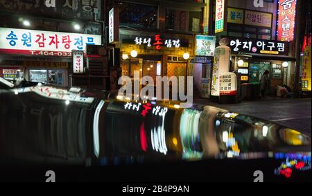 Busan, Südkorea - 23. März 2018: Nächtliche asiatische Stadtansicht mit heller Werbebeleuchtung, Menschen gehen die Straße Stockfoto