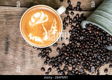 Latte Art Kaffee in Tasse auf Holztisch mit Kaffeebohnen-Business-Konzept Stockfoto