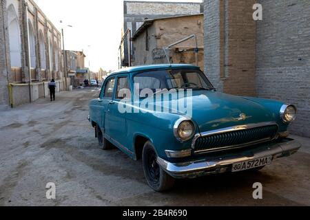 Altes Fahrzeug vor dem historischen Gebäude, im Stadtzentrum, Buchara, Usbekistan, Zentralasien Stockfoto