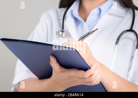 Ärztin schreibt medizinische Informationen in einem Notizbuch im Krankenhaus Stockfoto