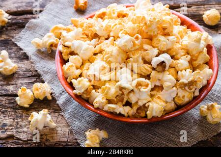 Popcorn in einer Schüssel und verstreut auf einem Tisch in der Nähe Stockfoto