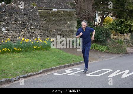 Ein passendes Mann, das in Burford, Oxfordshire, Großbritannien unterwegs ist Stockfoto