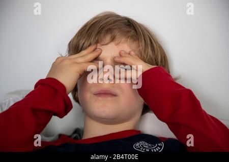 Kind mit Kopfschmerzen, Junge 9 Jahre alt, mit Schmerzen verzerrtes Gesicht, symbolisches Bild, Stockfoto