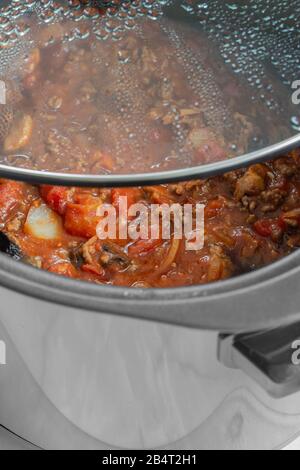 Bolognese Sauce Kochen in einem langsamen Herd mit Glasdeckel abgehoben. Selektive Farbe Stockfoto