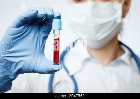 Nahaufnahme des Arztes, der eine schützende chirurgische Maske mit Blutprobe trägt - Konzept des epidemischen Virusausbruchs Stockfoto