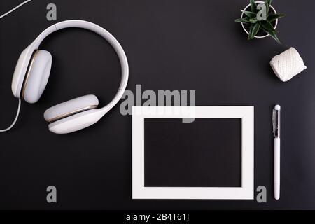 Mockup, Fotorahmen, Kopfhörer, Stift und Kaktus Write Objekt auf schwarzem Hintergrund Stockfoto