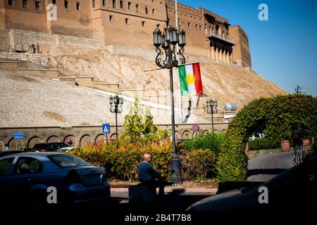 Ein Mann sitzt auf einem Grundstück die Zitadelle Qalat in Erbil hinunter. Stockfoto