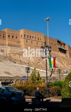 Ein Mann sitzt auf einem Grundstück die Zitadelle Qalat in Erbil hinunter. Stockfoto