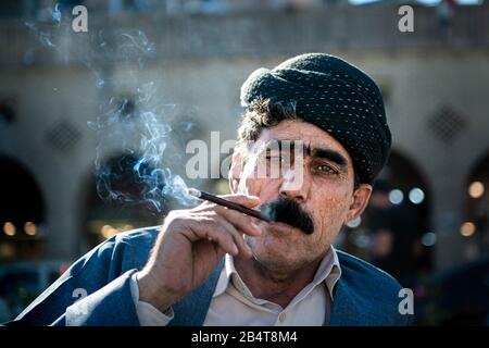 Irak, Iraq Kurdistan, Arbil, Erbil. Porträt eines irakischen kurden auf dem Park Shar. Rauch aus seiner Zigarette kommt aus dem Mund. Er ist Wea Stockfoto