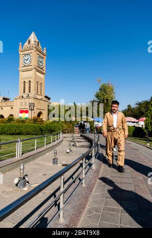 Irak, Iraq Kurdistan, Arbil, Erbil. Auf dem Park Shar läuft ein irakischer kurdenmann eine Gasse, die mit traditioneller kurdischer Kleidung bekleidet ist. Im Backgrou Stockfoto