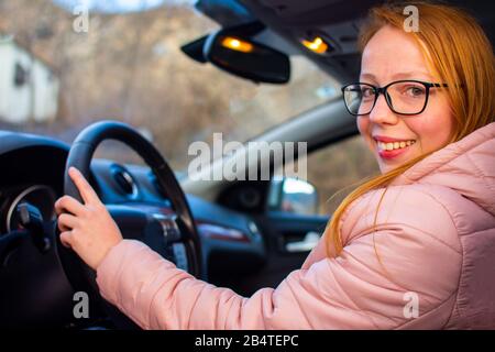 Mädchen, die hinter dem Rad eines Autos sitzen und lernen, wie man fährt Stockfoto